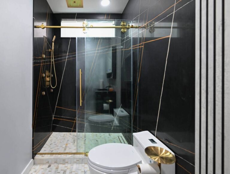 Shiny black bathroom wall with gold vertical stripes. Walk-in shower. Smart toilet.