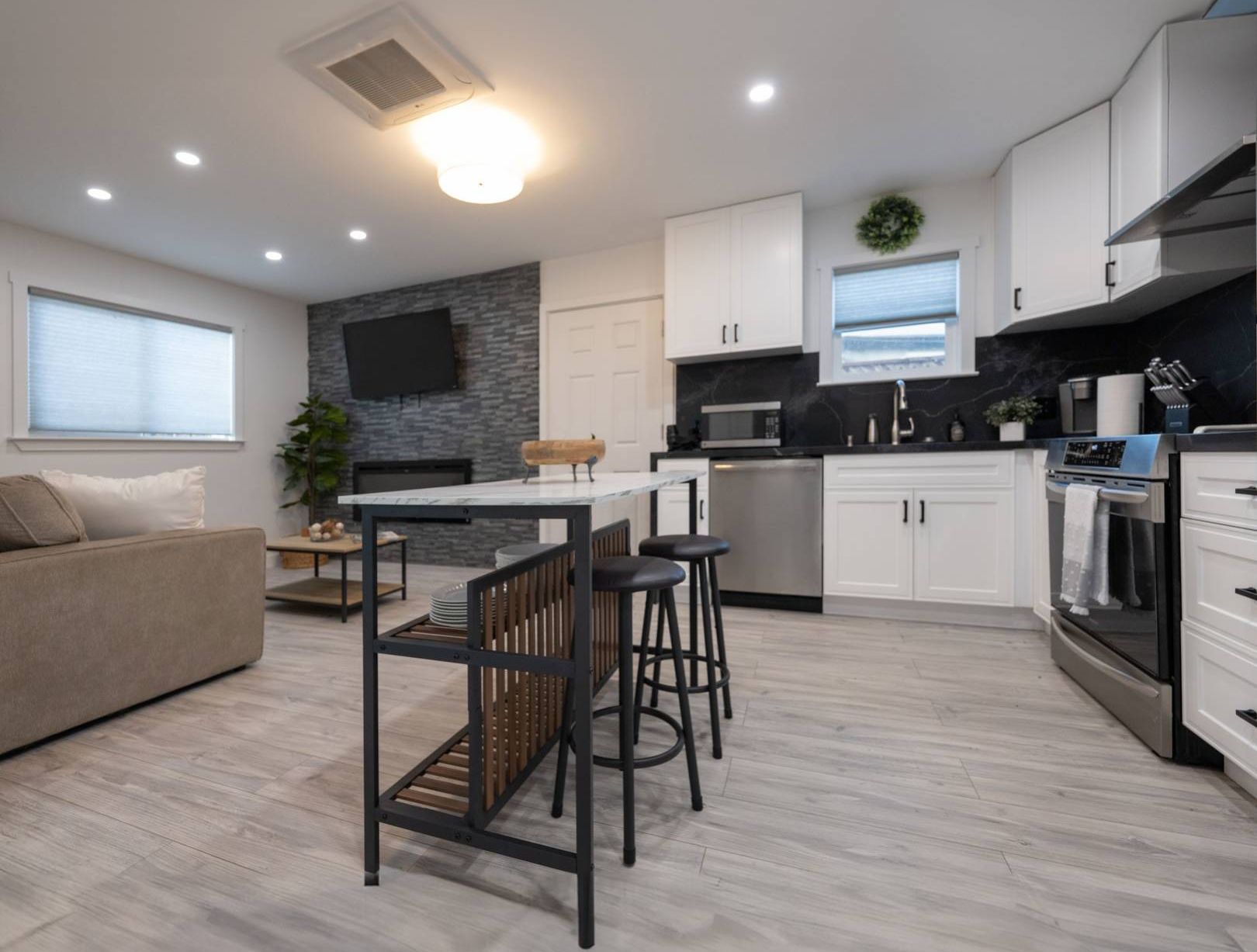 A modern kitchen and living room featuring a cozy couch and a stylish bar area for entertaining guests.