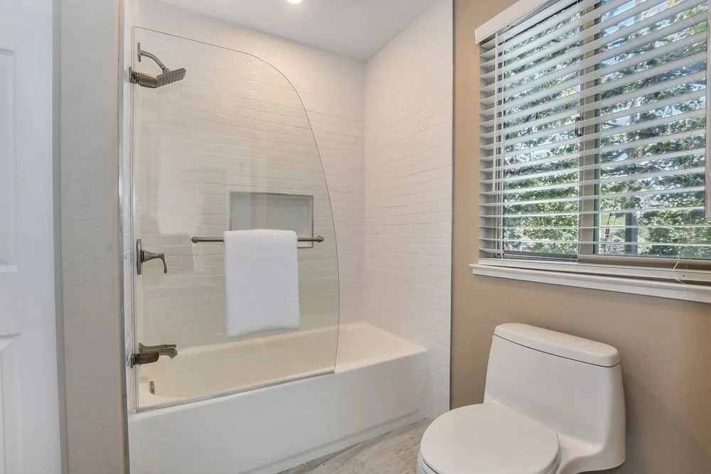 bathroom remodel with subway shower tile and curved glass